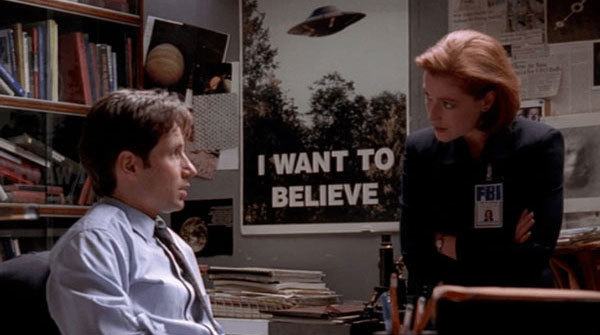 Fox Mulder and Dana Scully in front of the I Want To Believe poster