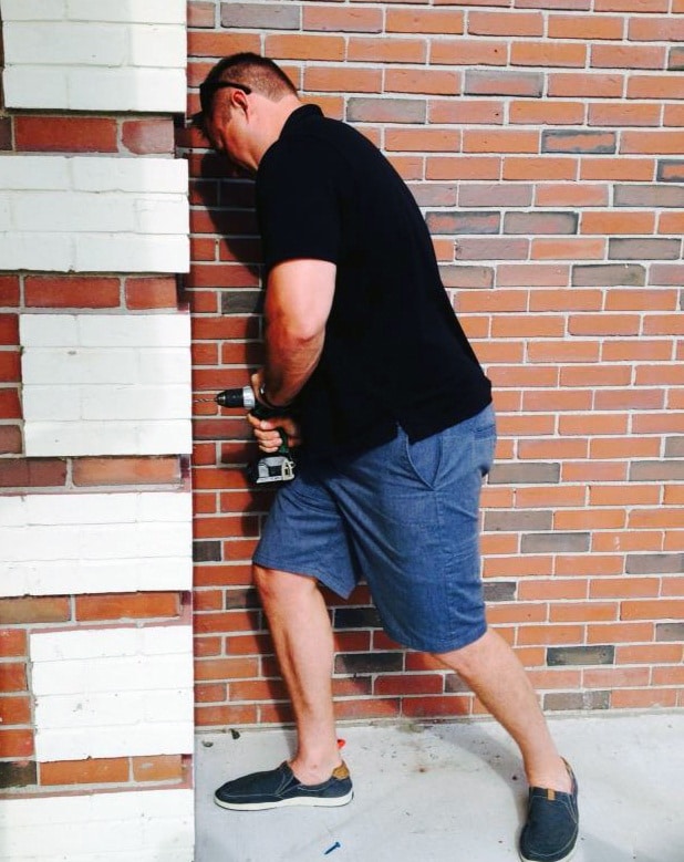 dr. drews using a power drill to install a mailbox