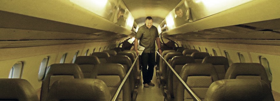 Dr. Drews walking down the aisle of a Concord airplane