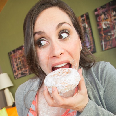 woman sneaking a powdered sugar donut snack