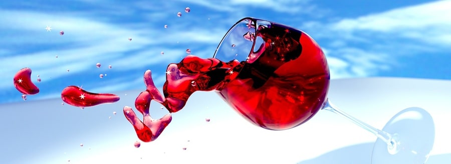 glass of red wine tipping over and splashing out