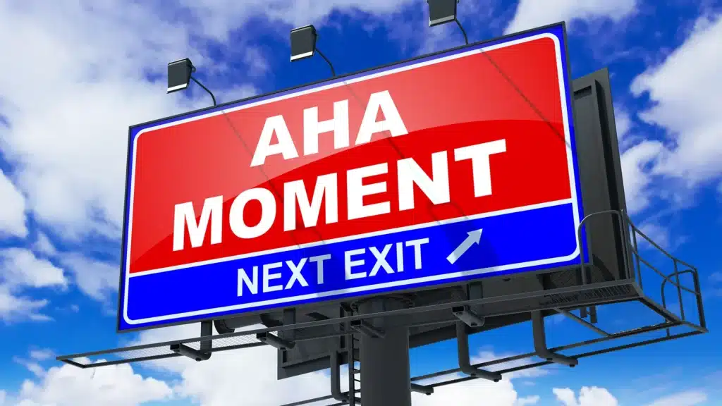 red billboard that says aha moment next exit with blue sky