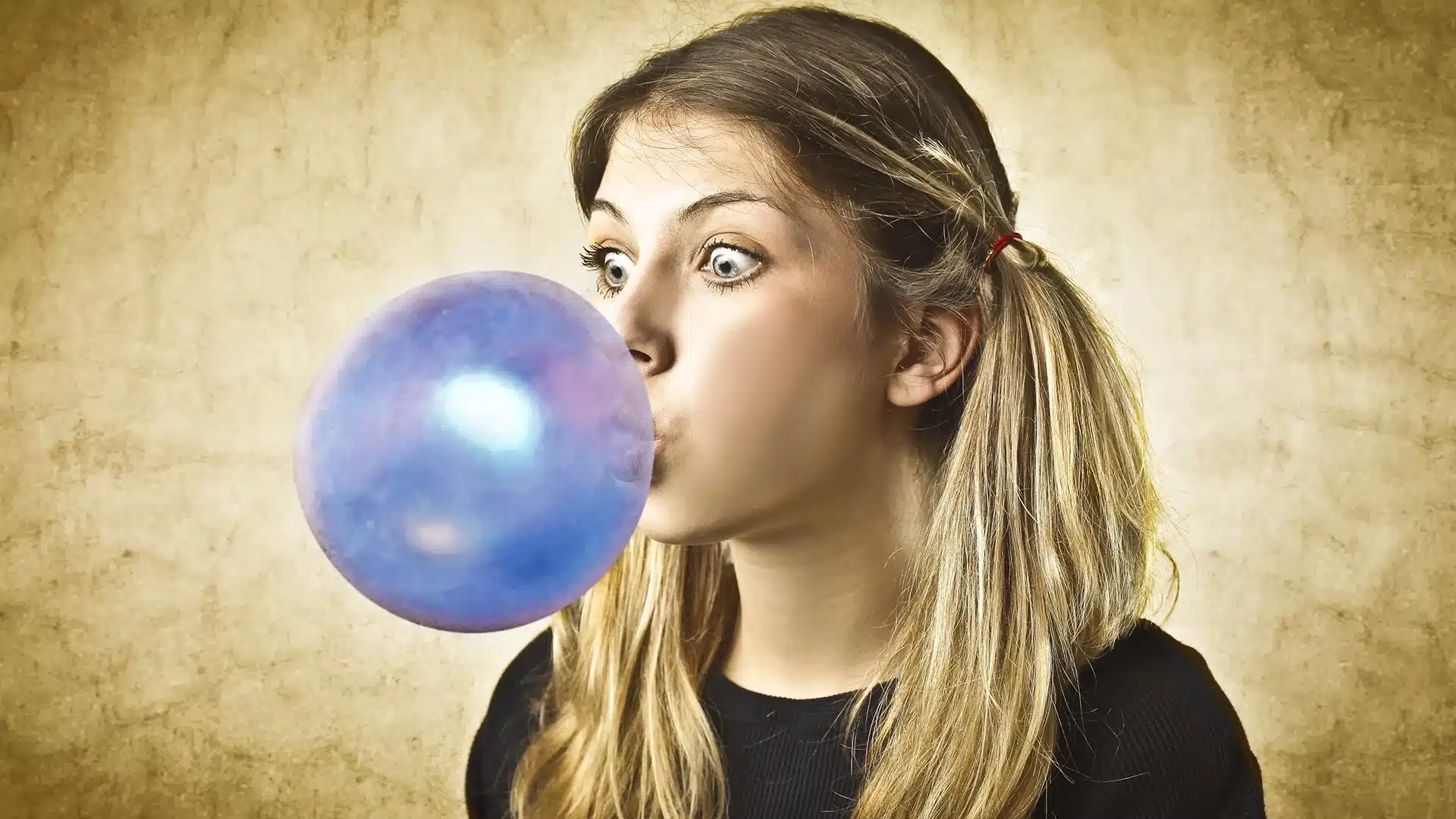 woman chewing bubble gum and blowing a bubble