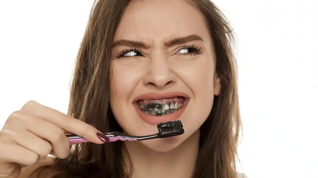 woman brushing with charcoal toothpaste