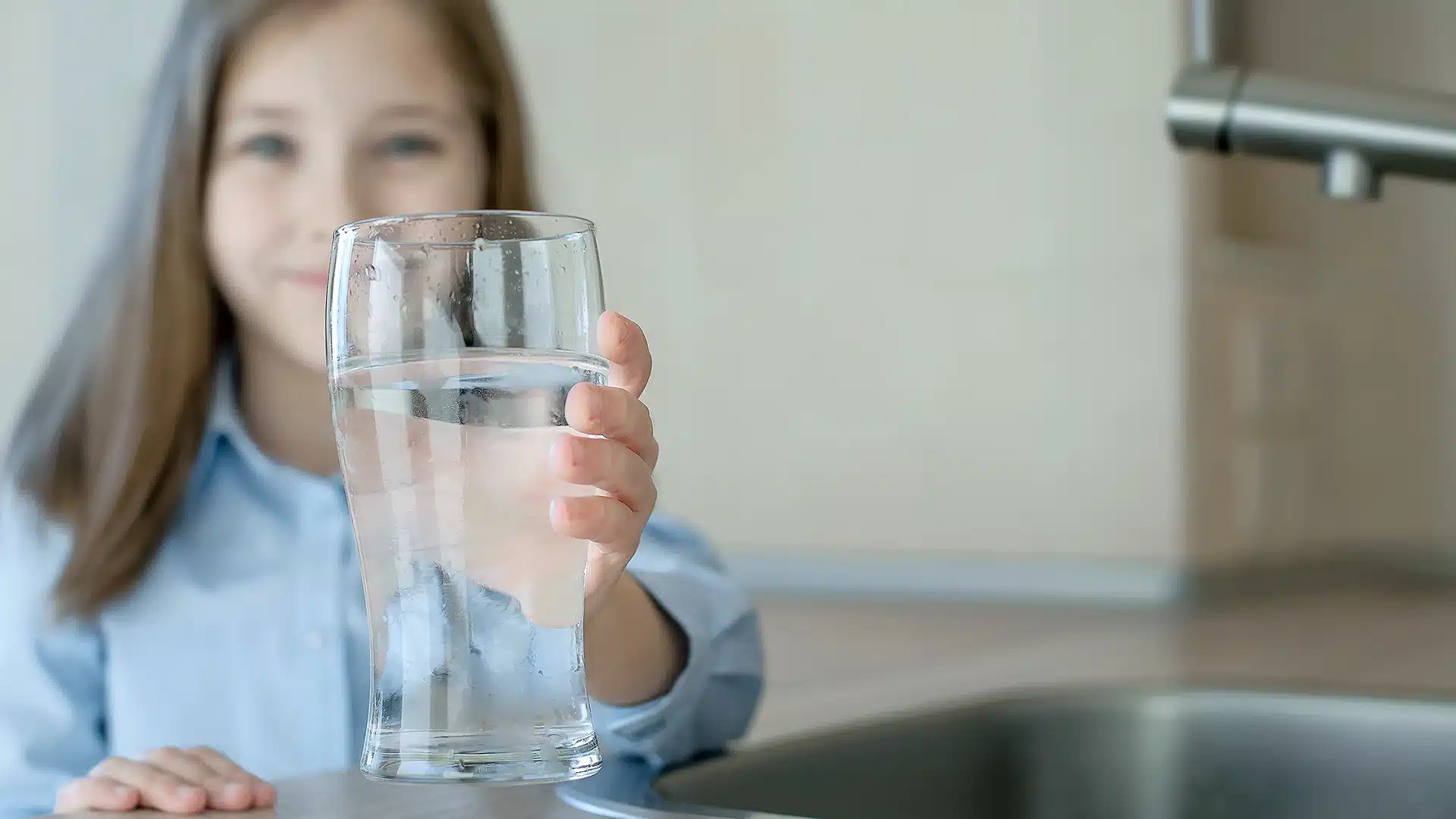 child holding a glass of fluoridated tap water