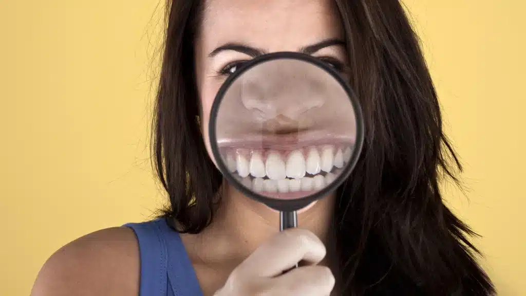 woman holding a magnifying glass to highlight her crowded front teeth