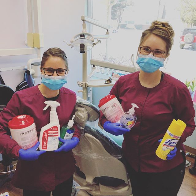 dental assistants wearing masks and holding various cleaning supplies