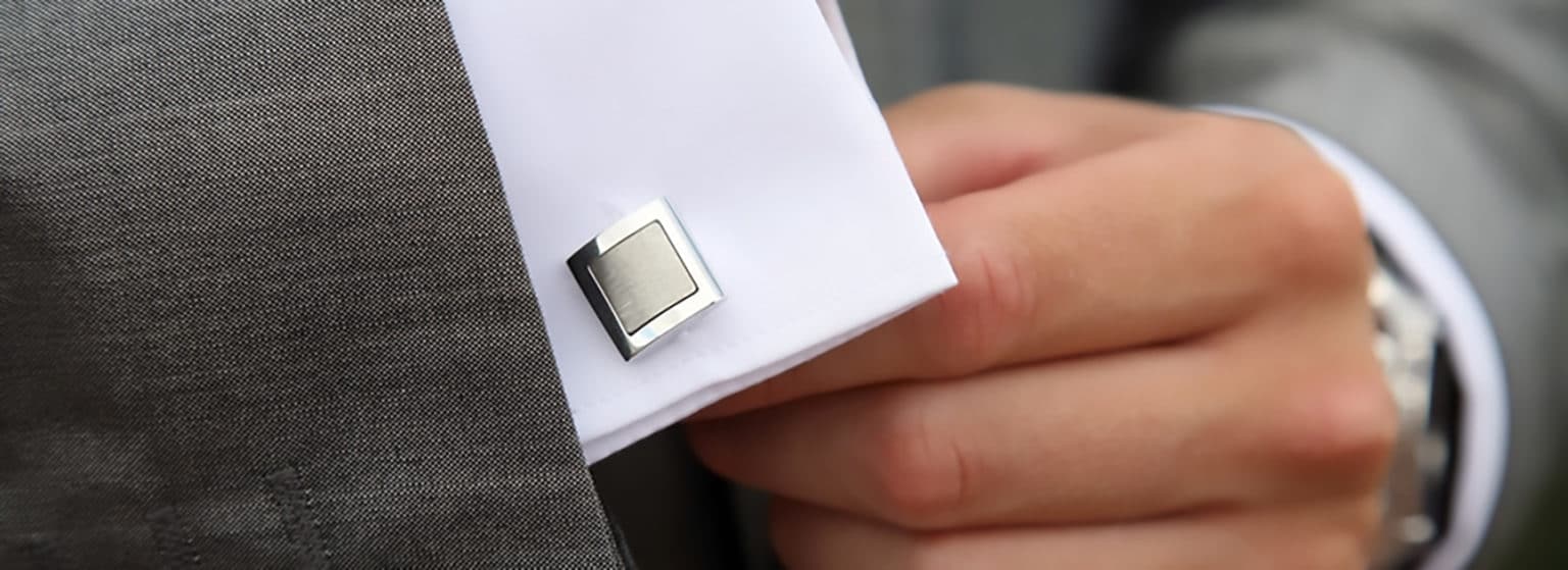 A man in a custom made suit adjusting his fancy cuff link