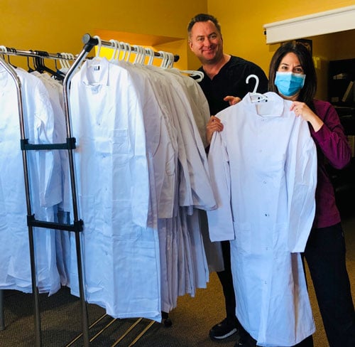 Peter and Karey showing off the clothing rack full of lab coats