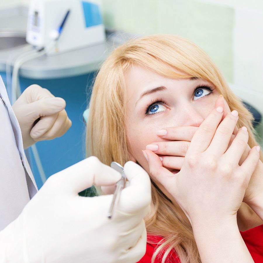 dental patient covering her mouth in fear of the drill