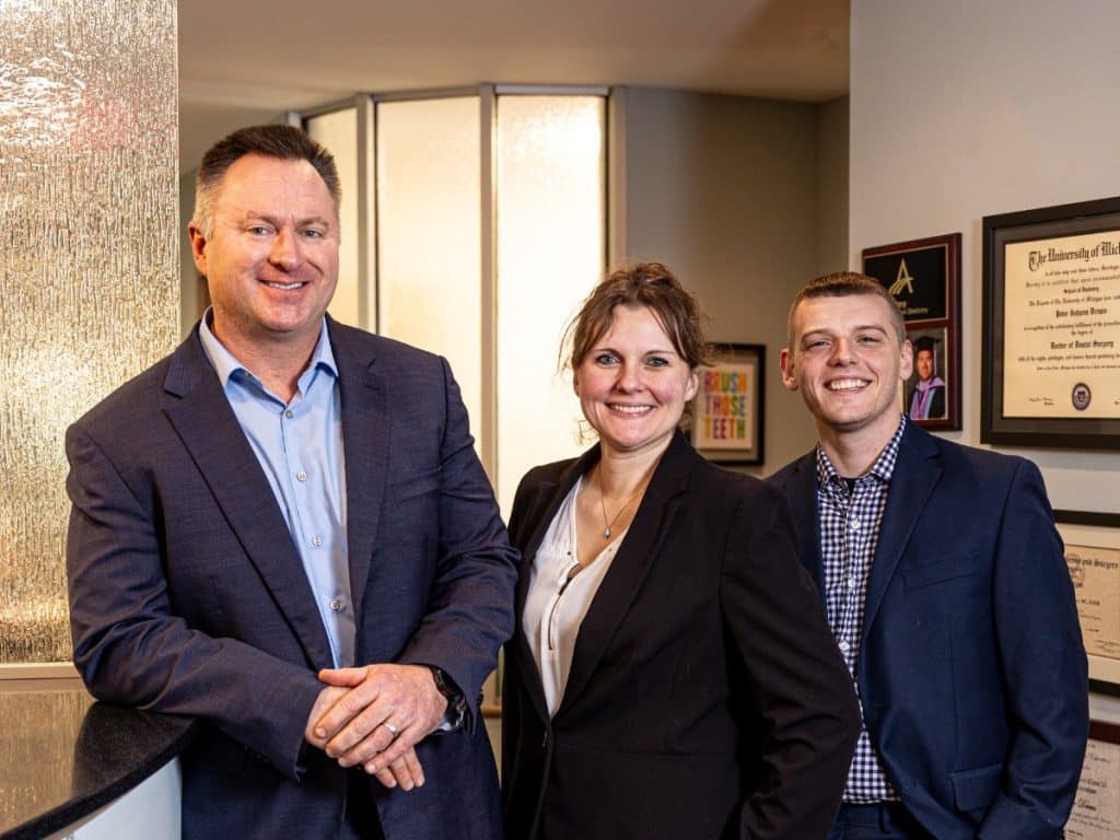 Three dentists from Drews Dental Services standing together in their Lewiston, Maine office