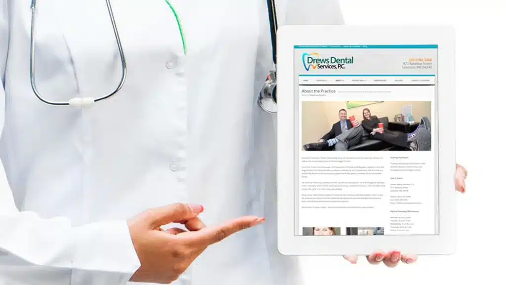 dr. in a white coat holding a tablet with drews dental service's website showing