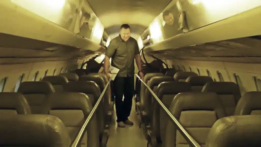 Dr. Drews walking down the aisle of a Concord airplane