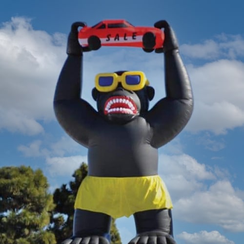 giant balloon gorilla holding a car that says sale