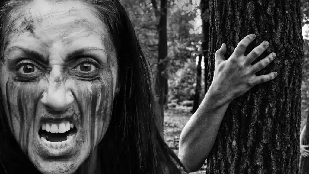 zombie woman with good teeth lurking in the spooky woods