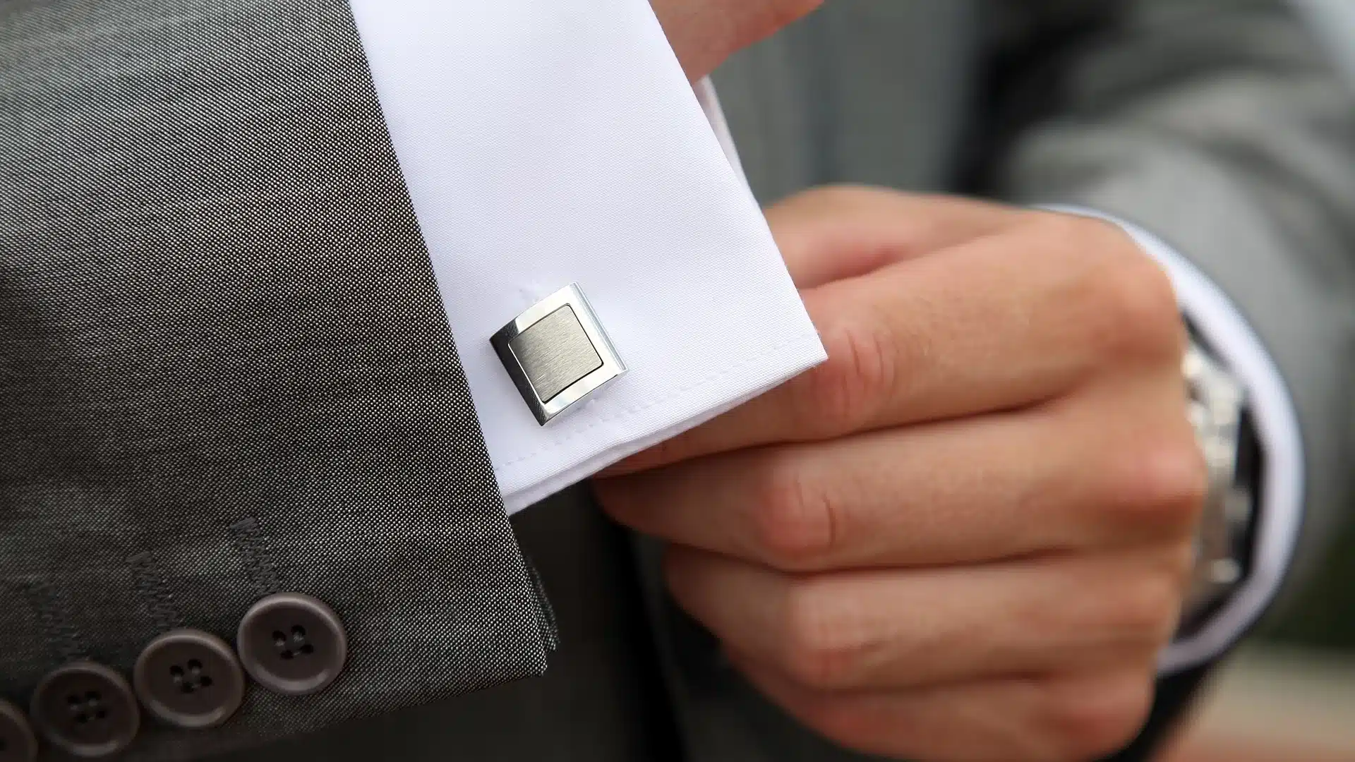 close up of a man in a custom suit adjusting his fancy cuff link
