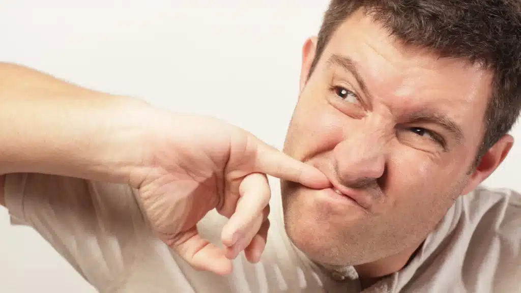 man awkwardly using his pinkie finger to pick food out of his teeth