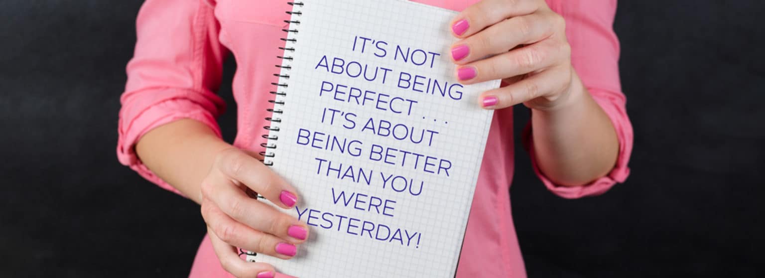 woman in a pink shirt holding a notebook that has a quote printed on it