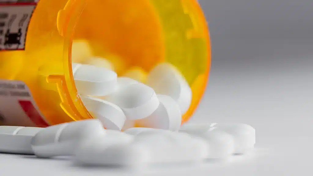 photo of a prescription pill bottle tipped over with pills falling out