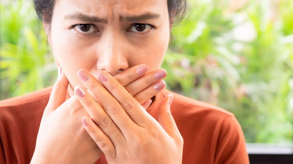 woman looking at the camera and holding her hands over her mouth
