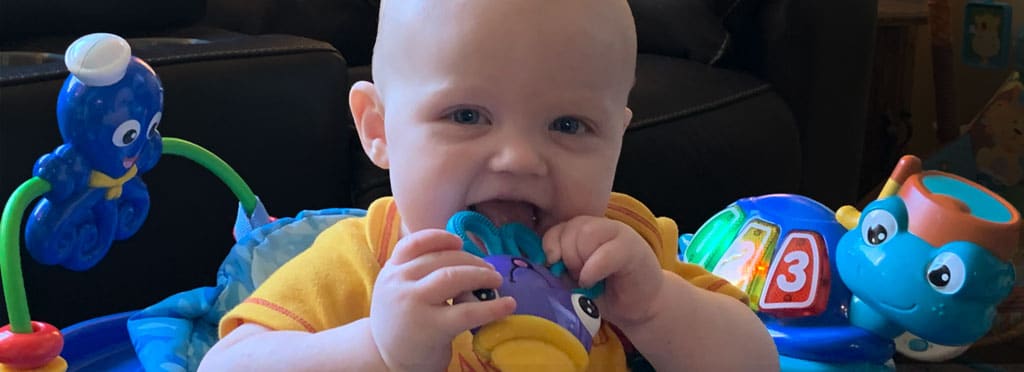 baby in a jumpy toy nibbling on a teething toy