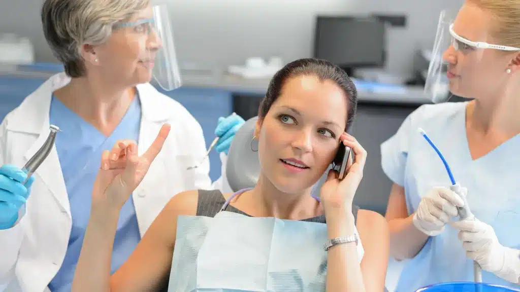 dental patient rudely talking on the phone while the dentist waits