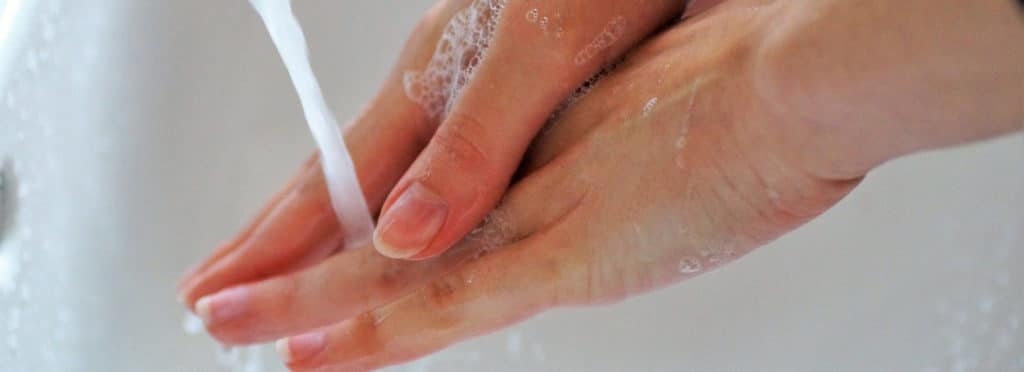 closeup of a woman's soapy hands under running water