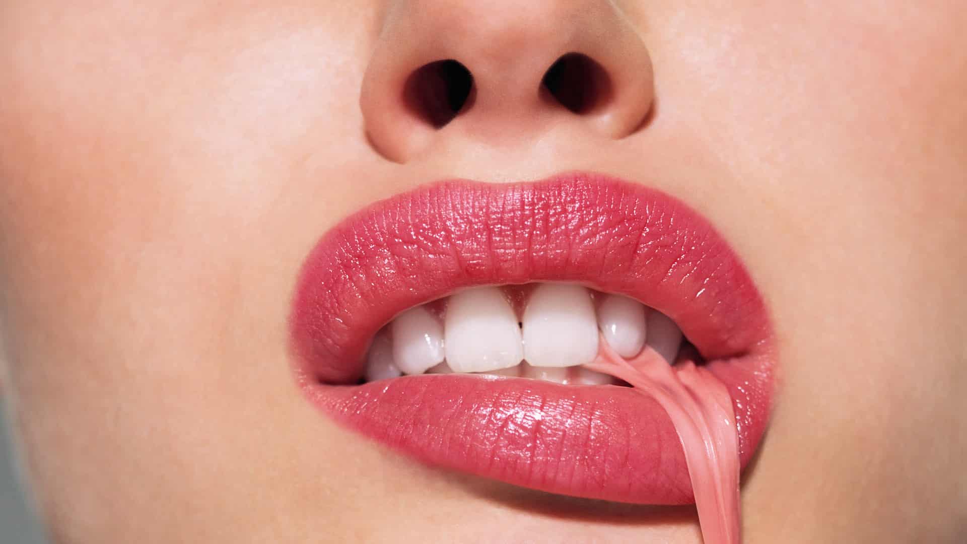 close up of a woman's mouth stretching chewing gum out