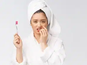 woman holding a toothbrush and worrying about bleeding gums