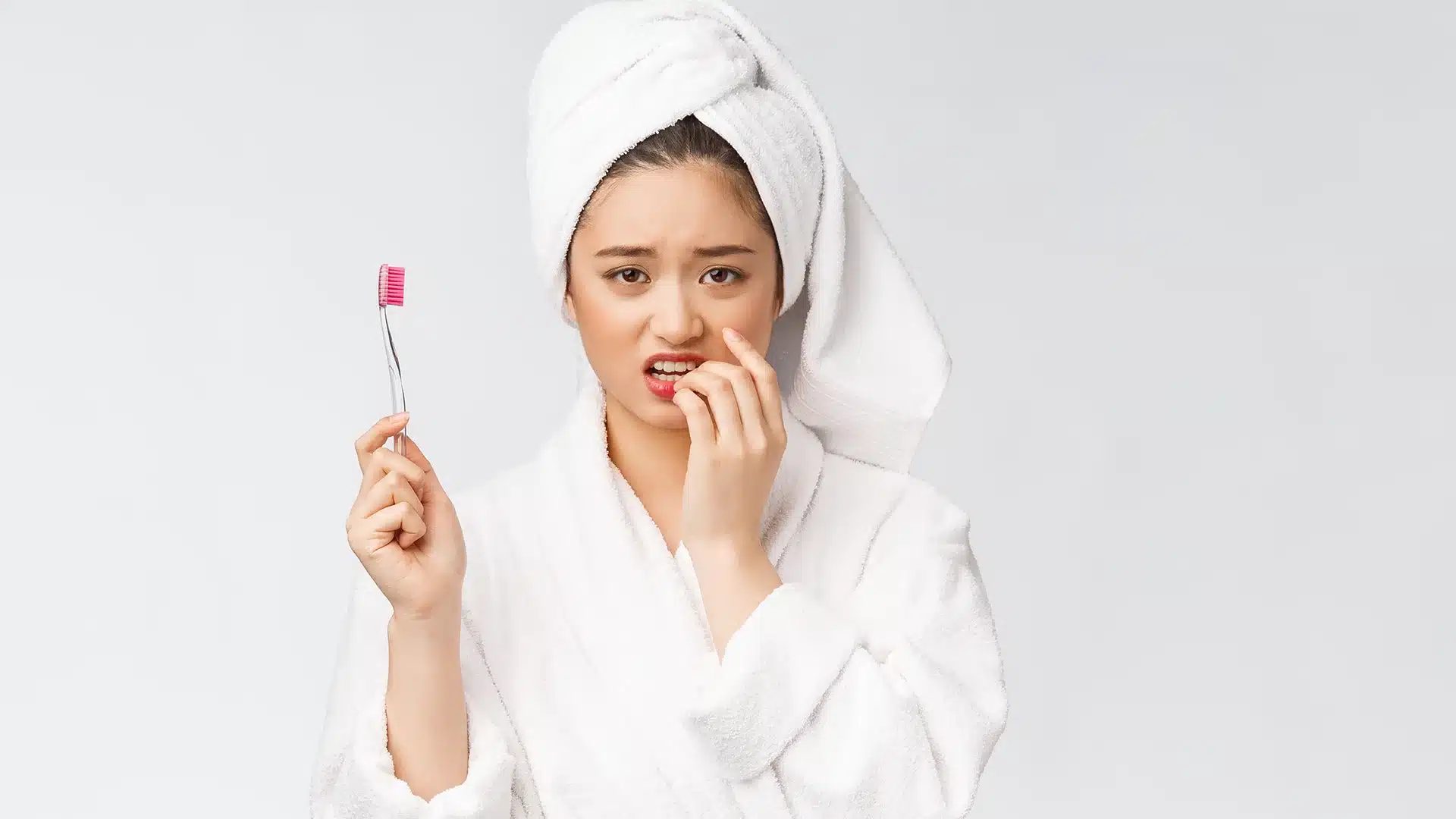 woman holding a toothbrush and worrying about bleeding gums